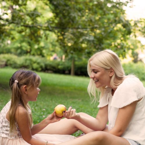 A mother and daughter smile as they enjoy a sunny day in the park